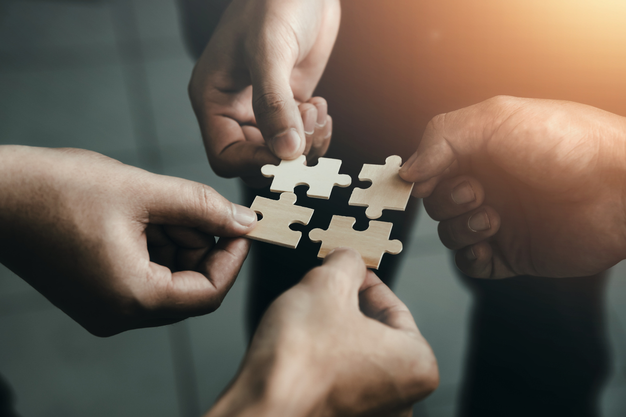 Handen die puzzelstukjes in elkaar leggen